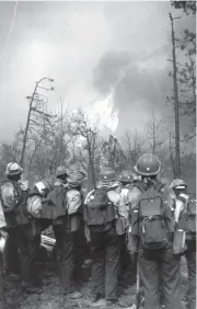  ?? REPUBLIC FILE PHOTO ?? Members of a hotshot crew from Redmond, Oregon, watch in 1990 as the Dude Fire moves up a slope in the Tonto National forest near Payson. The fire killed six people, destroyed dozens of homes and burned 25,000 acres of forest.