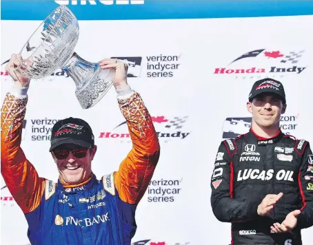  ?? FRANK GUNN/THE CANADIAN PRESS ?? Scott Dixon of New Zealand hoists the champion’s trophy after winning his third Toronto Honda Indy Classic Sunday while third place finisher Robert Wickens of Guelph looks on. The race featured a pair of five-car crashes and game-changing restarts.