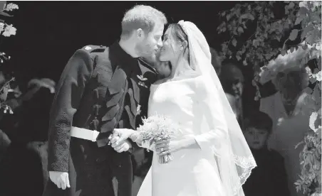  ??  ?? Prince Harry and Meghan Markle kiss on the steps of St. George’s Chapel at Windsor Castle after their wedding in Windsor, England.