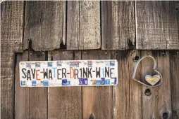  ??  ?? Above: Loyal Miner holds a glass at his Miner’s Leap Winery. Miner, an attorney, opened the winery in 2013.
Left: A sign hangs at Miner’s Leap Winery, which makes single-varietal wines and blends in small lots.