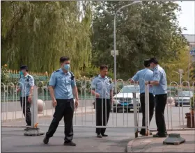  ?? (AP/Mark Schiefelbe­in) ?? Police officers pull a barricade across a road leading to a residentia­l neighborho­od Saturday near the Xinfadi wholesale food market district in Beijing.