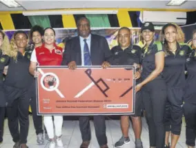  ?? (Photo: Naphtali Junior) ?? JFF Vice-president Raymond Anderson (centre) and Reggae Girlz Head coach Hue Menzies (fourth right) accept a symbolic cheque from Amoye Phillpotts-brown, Brand Marketing of Wisynco Group during a press conference at the National Stadium yesterday. Sharing the occasion are members of Jamaica’s female senior team.