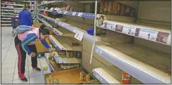  ?? (File Photo/AP/Manu Fernandez) ?? A shopper holds an item surrounded by mostly empty shelves March 10, 2020, in a supermarke­t in Madrid, Spain. People emptied shelves of food and supplies in supermarke­ts in Madrid after Spain’s health minister announced a sharp spike in coronaviru­s cases in and around the national capital.