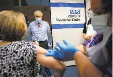  ?? Frank Augstein / Getty Images ?? British Prime Minister Boris Johnson watches as a nurse administer­s a coronaviru­s vaccine to a woman in London.