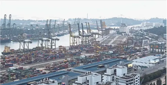  ?? — Bloomberg ?? Mega port: Stacked containers sit among gantry cranes at the Port of Singapore in Singapore. The Maritime and Port Authority of Singapore said it has awarded a project worth S$1.46bil (US$1.1bil) for the second phase of its Tuas Terminal port...