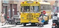  ?? File photo ?? A bus staff member helps students cross the streets with the help of the stop sign board on the side of the bus. —