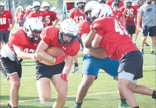  ?? RICK PECK/SPECIAL TO MCDONALD COUNTY PRESS ?? McDonald County running back Bailey Lewis runs through a hole during a workout on July 23 at MCHS.