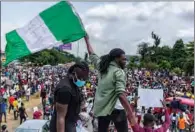  ?? (AFP) ?? A Nigerian youth waves national flag in support of the ongoing protest against the unjust brutality of the Nigerian police unit Special AntiRobber­y Squad (SARS) in Lagos on Tuesday.