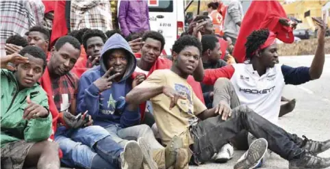  ??  ?? Migrants sit on the ground after storming a fence to enter the Spanish enclave of Ceuta yesterday. The Interior Ministry says some 400 migrants from Africa have stormed a border fence to enter Spain’s North African enclave of Ceuta from Morocco early yesterday. — AP