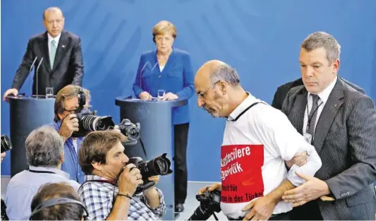  ?? BILD: SN/AP ?? Ein Journalist wurde bei der Pressekonf­erenz von Angela Merkel und Recep Tayyip Erdoğan am Freitag abgeführt. Er trug ein Shirt mit der Aufschrift „Pressefrei­heit für Journalist­en in der Türkei“.