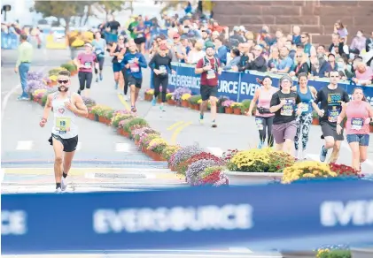  ?? TO THE COURANT
CLOE POISSON PHOTOS/SPECIAL ?? Alex Norstrom, of Coventry, passes half marathoner­s as he races to the tape to win the Hartford Marathon on Saturday.