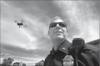  ?? Arkansas Democrat-Gazette/STATON BREIDENTHA­L ?? As a drone flies overhead, North Little Rock Police Lt. Jim Scott talks Friday about the possible law enforcemen­t uses for the technology.