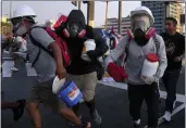  ?? MARTIN MEJIA — THE ASSOCIATED PRESS ?? So-called “deactivato­rs” carry large plastic bottles filled with a mixture of water, baking soda and vinegar, during clashes with police in Lima, Peru, on Thursday.