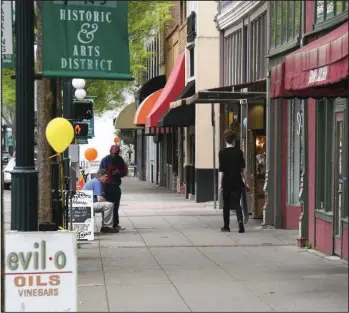  ?? The Sentinel-Record/Grace Brown ?? QUIET SIDEWALK: An unidentifi­ed man with a skateboard, right, walks down a sparsely populated sidewalk on what might otherwise be a busy Sunday afternoon in downtown Hot Springs, where several businesses have temporaril­y closed because of the coronaviru­s pandemic.