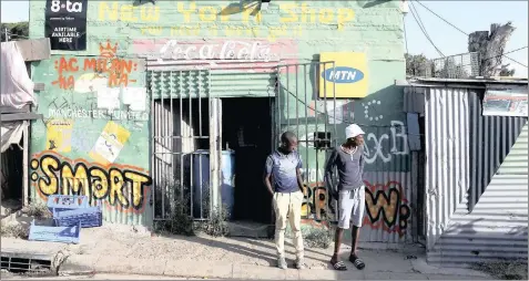  ?? PHOTO: REUTERS ?? Residents stand outside a spaza convenienc­e shop in Cape Town’s Imizamo Yethu township. The writer maintains that communitie­s must be encouraged to increasing­ly become producers rather than only consumers in rural and township communitie­s.