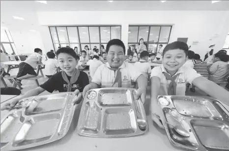  ?? LIU BIN / XINHUA WANG ZHENG / FOR CHINA DAILY ?? Left: Primary school students in Deqing county, Huzhou, Zhejiang province, show they have cleared their lunch plates. ernment building in Beijing.