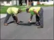  ?? SUBMITTED PHOTO ?? Valley Township Streets Department employees Brian Myers and Josh Waltrop cover up racial graffiti on Wednesday that was painted on West 10th Avenue in the township.