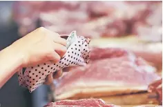  ??  ?? A customer takes a 50 Yuan note out as she pays for meat at a market in Beijing, China. With China’s Lunar New Year festivitie­s fast approachin­g, swine farmers in the world’s biggest pork market have little to cheer. As they fatten herds to meet peak demand, a slump in retail prices and a spike in feed costs are grinding up profits. — Reuters photo