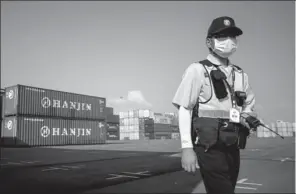  ?? ED JONES / AFP ?? A security guard walks by containers at the Hanjin Incheon Container Terminal in Seoul. China COSCO Shipping Corp said it may consider buying some container-terminal assets of the troubled Hanjin Shipping Co.