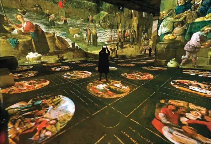  ??  ?? People look at projection­s of paintings as part of the exhibition ‘The Fantastic and Wonderful world of Bosch’, Brueghel, Arcimboldo at the Quarries of Lights (Carrieres de Lumiere) in Les Baux-de-Provence. — AFP