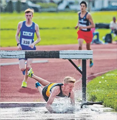  ?? BOB TYMCZYSZYN
THE ST. CATHARINES STANDARD ?? Nick Reimer from Sir Winston Churchill Secondary School slips off the steeplecha­se hurdle in the men’s 1500m during the Zone 4 track and field meet at the Niagara Olympic Club.