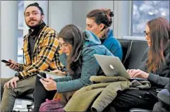  ??  ?? Mehmet Aytekin, left, left, checks his cellphone Friday while waiting to board his United Airlines flight to Newark, N.J. at O’Hare Internatio­nal Airport.