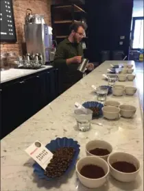  ?? BETH J. HARPAZ, THE ASSOCIATED PRESS ?? Beans and ground coffee set out in cups for a tasting known as a "cupping" at Parlor Coffee in Brooklyn, New York, with tasting room manager Peter Higgins at the other end of the counter.