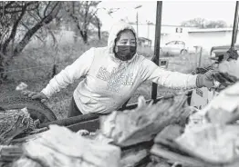  ?? ?? Alyssa Villarreal refills a wheelbarro­w with wood to sell at her street vending stand, which is set up beside Andy’s Ice House on the South Side.