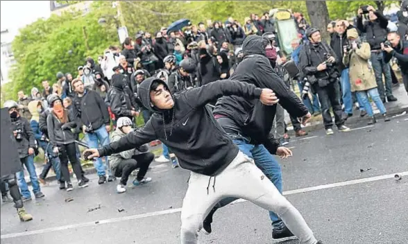  ?? MIGUEL MEDINA / AFP ?? Unos manifestan­tes lanzando piedras contra la policía, ayer durante las protestas de París en desacuerdo con la reforma laboral