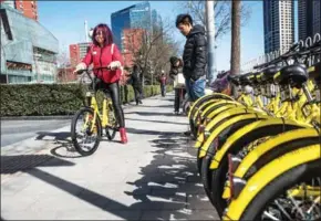  ?? GILLES SABRIE/THE NEW YORK TIMES ?? A commuter picks up an Ofo bike in Beijing, March 1.