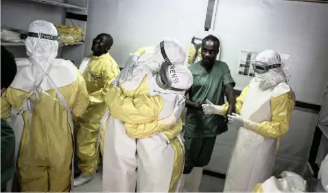  ?? JOHN WESSELS ?? HEALTH workers embrace while putting on their protective equipment before heading to work at an MSF-supported Ebola treatment centre. |