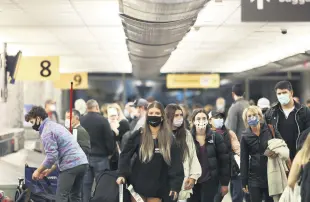  ??  ?? Travelers wearing protective masks to prevent the spread of the coronaviru­s outbreak reclaim their luggage at the airport, Denver, Colorado, U.S., Nov. 24, 2020.