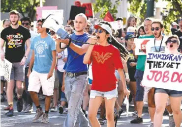  ?? STAFF PHOTO BY ROBIN RUDD ?? Alondra Gomez leads a march Saturday along Broad Street while her husband, Jared Steiman, holds a megaphone. The Tennessee Immigrant and Refugee Rights Coalition held the march in downtown Chattanoog­a in support of the Deferred Action for Childhood...