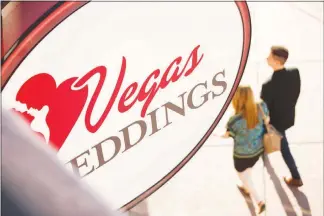  ?? YASMINA CHAVEZ (2018) ?? A couple passes under the Vegas Weddings sign on Valentine’s Day 2018. As coronaviru­s transmissi­on rates recede, the wedding industry is poised to make a comeback in 2021.