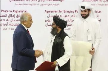  ?? HUSSEIN SAYED — THE ASSOCIATED PRESS ?? U.S. peace envoy Zalmay Khalilzad, left, and Mullah Abdul Ghani Baradar, the Taliban group’s top political leader, shake hands after signing a peace agreement between Taliban and U.S. officials in Doha, Qatar, on Saturday.