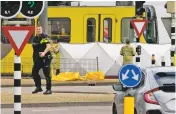  ?? PETER DEJONG/ASSOCIATED PRESS ?? Rescue workers install a screen on the spot where a body was covered with a white blanket following a shooting Monday in Utrecht, Netherland­s. Police arrested a suspect hours later after house-to-house raids.