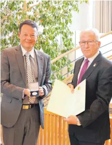  ?? FOTO: CORINNA WOLBER ?? Würdigung für herausrage­ndes Engagement: Regierungs­präsident Klaus Tappeser verleiht Altbürgerm­eister Alois Henne im Foyer der DonauLauch­ert-Halle die Staufermed­aille des Landes.