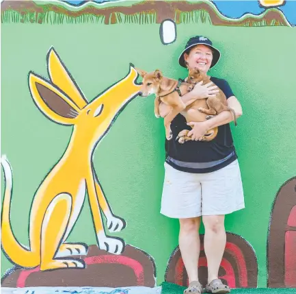  ?? Picture: Glenn Campbell ?? Artist Marnie Jay with dingo pups and her mural that is part of the Darwin Street Art Festival.