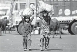  ?? Channi Anand
Associated Press ?? ON THE OUTSKIRTS of Jammu, India, children carry sacks of leftover vegetables collected from a wholesale market. The food will be sold in their shantytown.