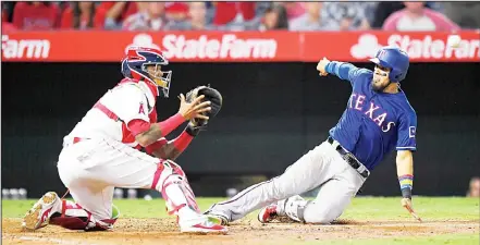  ??  ?? Texas Rangers’ Robinson Chirinos (right), slides into home while trying to score on a single by Shin-Soo Choo as Los Angeles Angels catcher Martin
Maldonado waits for the throw during the ninth inning of a baseball game, on Aug 23, in Anaheim,...