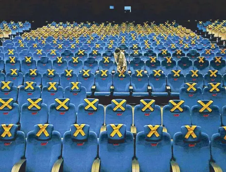  ?? REUTERS ?? A worker marks seats for social distancing at a movie theater at CGV cinema amid the coronaviru­s pandemic in Jakarta, Indonesia on Wednesday.