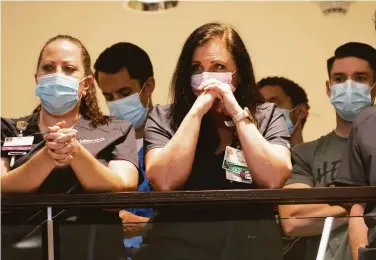  ?? J Pat Carter / Getty Images ?? St. Francis Hospital employees listen to a news conference discussing the deadly shooting in Tulsa, Okla.