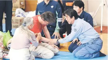  ??  ?? Abe (right) visits a shelter for people affected by the recent flooding in Mabi, Okayama prefecture. — AFP photo