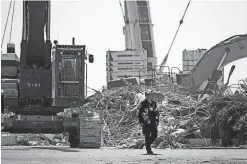  ?? ANNA MONEYMAKER/GETTY IMAGES VIA TNS ?? A rescue worker walks away from the remains of the collapsed 12-story Champlain Towers South condo building in Surfside, Fla., on Thursday.