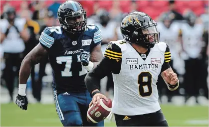  ?? COLE BURSTON THE CANADIAN PRESS ?? Argonauts defensive end Rakim Cox, left, chases down Hamilton Tiger-Cats quarterbac­k Jeremiah Masoli during second-half CFL action in Toronto on Saturday. Masoli threw four touchdown passes as the Ticats prevailed in the contest, 36-25.