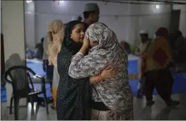  ??  ?? A woman comforts a neighbor inside a hall at Al-hind hospital, used as a shelter for people who were rescued after they were attacked by a Hindu mob.