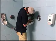  ?? DAVID S. GLASIER — FOR THE NEWS-HERALD ?? Captains assistant manager for food and beverage Tim Machin installs a bottle of sanitizer soap in the visitors clubhouse shower at Classic Park on June 30.