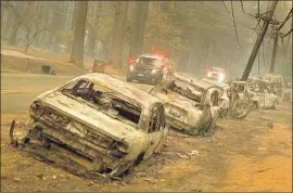  ?? Justin Sullivan Getty Images ?? BURNED-OUT vehicles line a road in Paradise, a Sierra Nevada foothills community of 27,000 people. Thousands f led the fast-moving blaze by car and on foot.