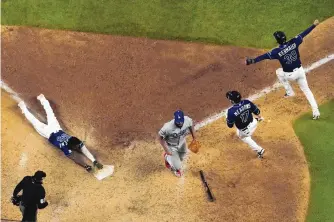  ?? DAVID J. PHILLIP/ASSOCIATED PRESS ?? Tampa Bay’s Randy Arozarena reaches out to score the winning run in the ninth inning as the Rays rallied for two runs in the frame to win Game 4 and tie the World Series at 2-2.