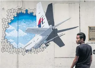  ??  ?? A man in front of a Malaysian Airlines flight MH370 mural painting at Shah Alam, outside Kuala Lumpur, Malaysia.